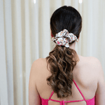 brunette girl wearing  pink flower scrunchie